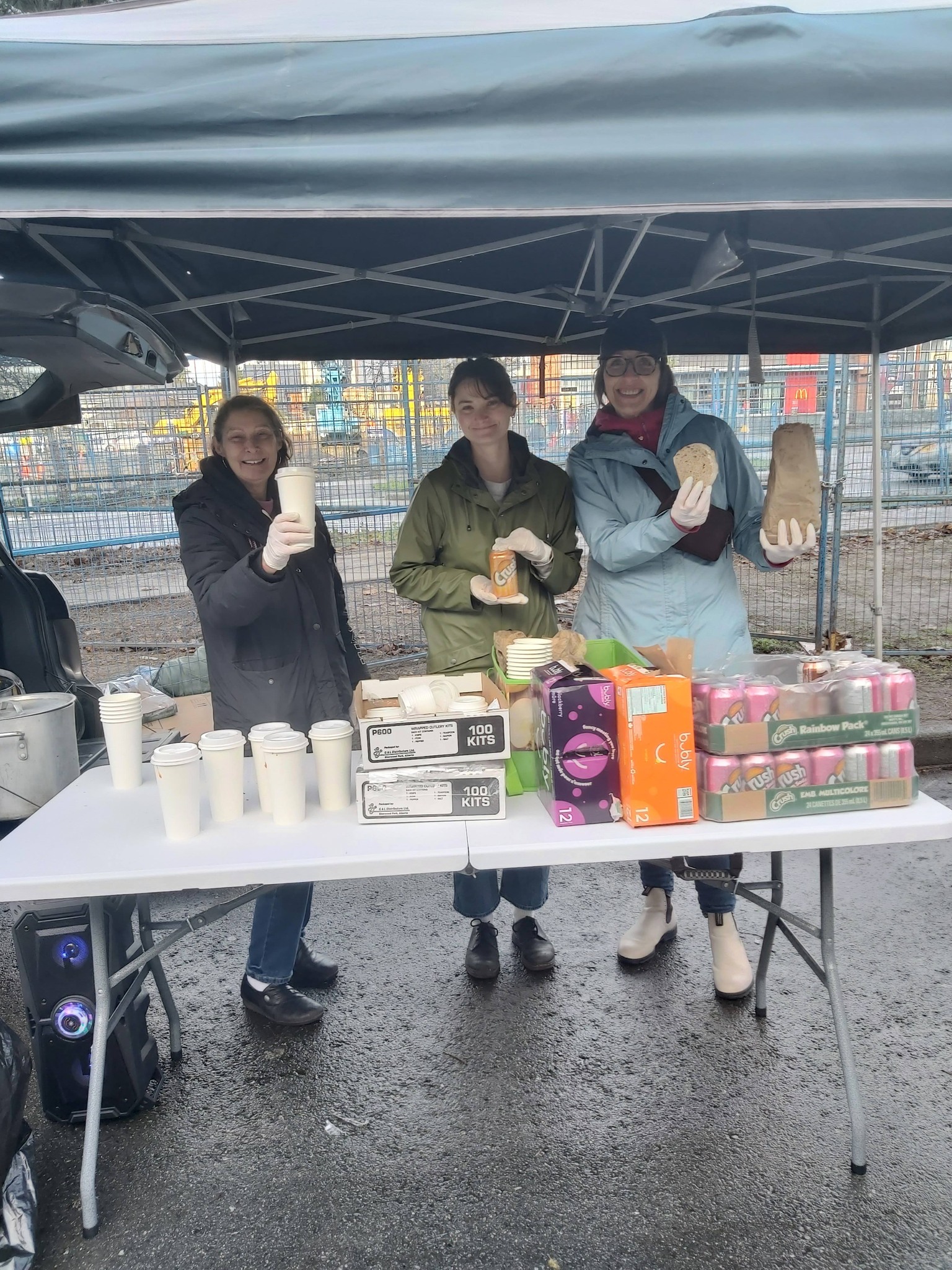 Three women handing out soup, bread and a drink